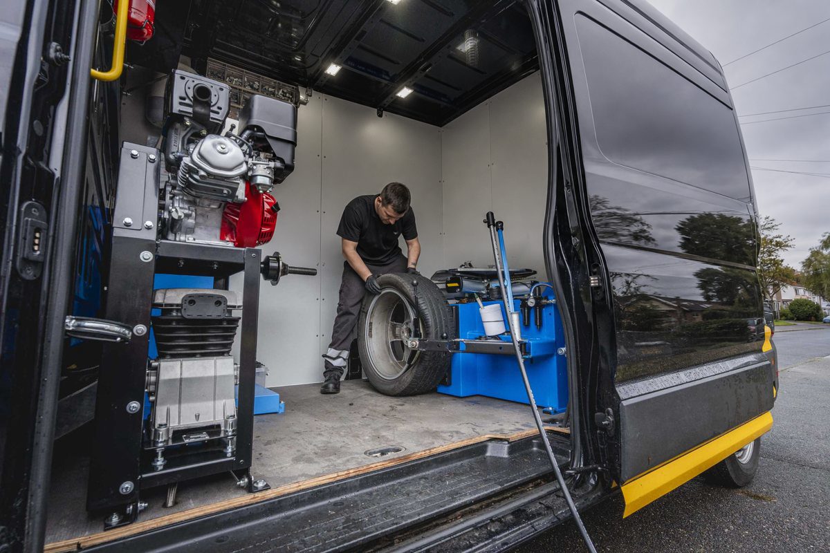 Technician changing a tyre inside a mobile tyre service van